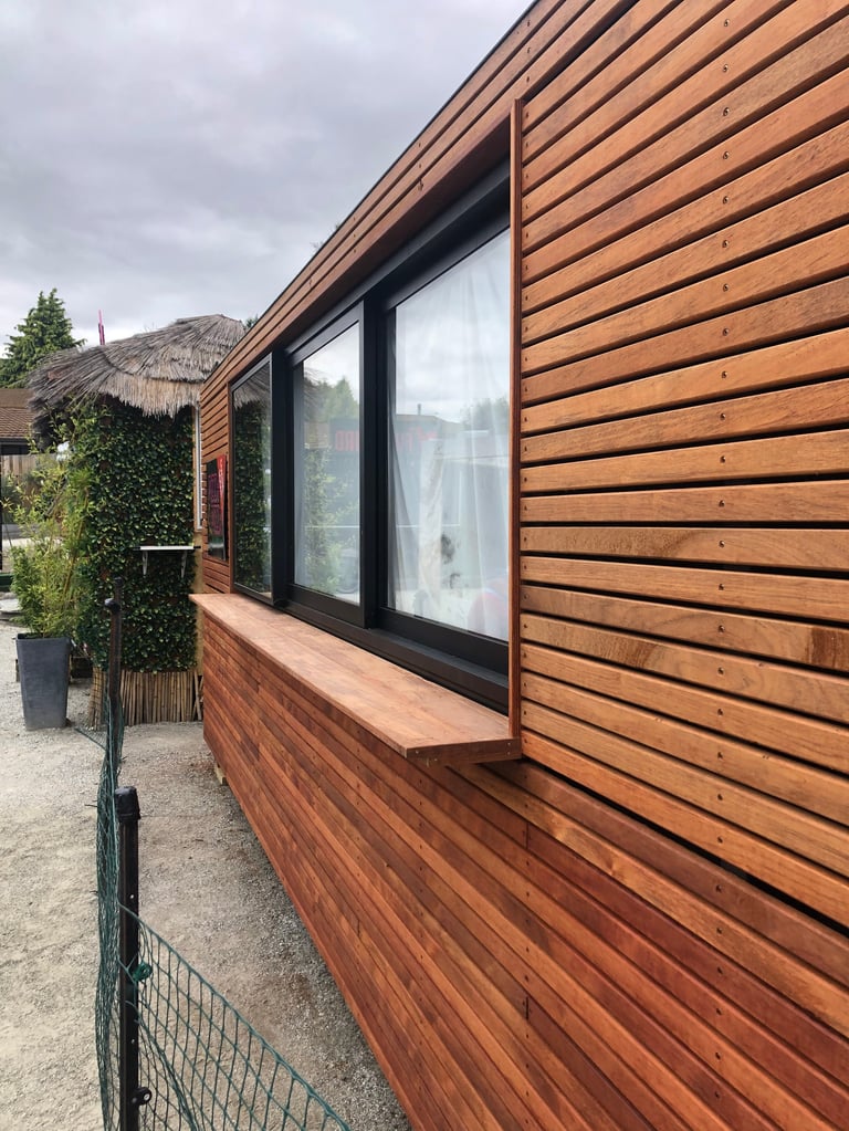 Modern wooden cabin exterior with horizontal timber cladding and large black-framed windows