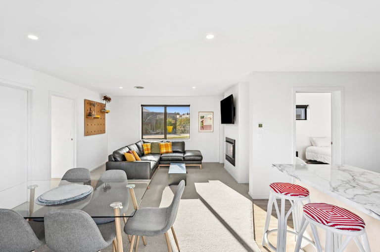Modern open-plan living space with dining table, gray sectional sofa, yellow accent pillows