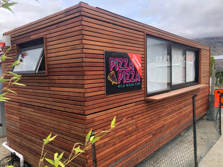 Wooden mobile food stand with neon Pizza Pizza sign visible on the storefront window